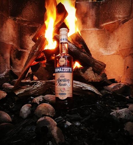 a bottle of alcohol sitting on rocks in front of a fire at Hotel Nubes de Quinchao in Quinchao