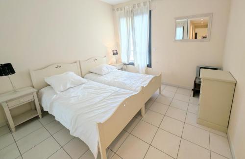 une chambre blanche avec un lit et une fenêtre dans l'établissement Ref FLORIAN by Palmes dProperties, à Cannes