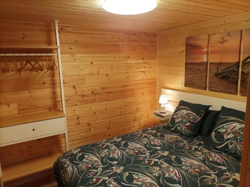 ein Schlafzimmer mit einem Bett in einem Holzzimmer in der Unterkunft Cottage "Au ptit bonheur" in Bourbourg