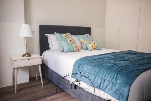 a bedroom with a bed with a blue blanket and a table at Sunflower Studio in Braga