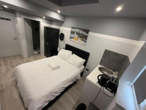 a small bedroom with a white bed and a table at Letzi Ensuite, 15 Min to Heathrow, Fast WiFi in Hayes