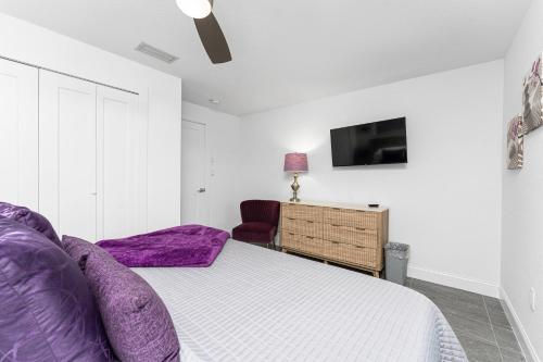 a bedroom with a bed with purple pillows and a tv at Villa Tranquility-Waterfront-Punta Gorda, FL in Punta Gorda