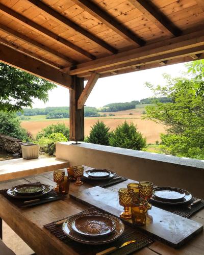 - une table en bois avec des assiettes de nourriture sur une terrasse couverte dans l'établissement Le Parasol Rouge, à Saint-Sylvestre-sur-Lot