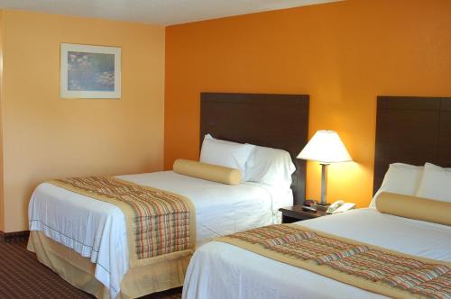 a hotel room with two beds and a lamp at Budgetel Inn Glens Falls-Lake George-Saratoga in Glens Falls