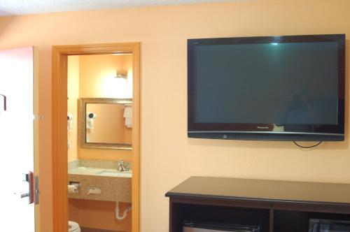 a flat screen tv on the wall of a bathroom at BLUE SKY INN Glens Falls-Saratoga-Lake George in Glens Falls