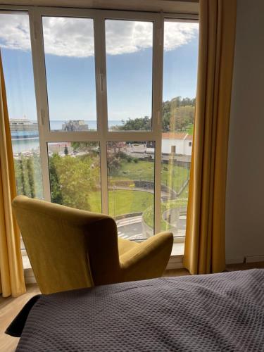 une chambre avec une grande fenêtre avec une chaise devant dans l'établissement Center Marina view Yellow Studio, à Funchal