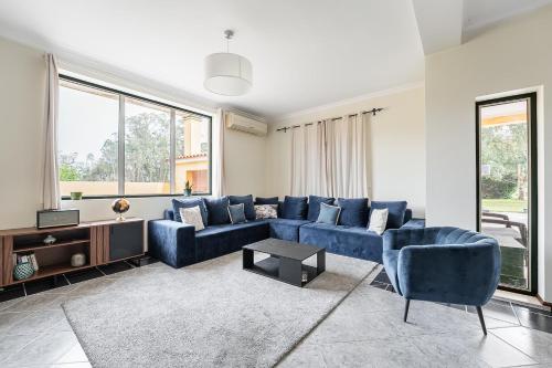 a living room with blue furniture and large windows at GuestReady - Quinta do Sol in Antes