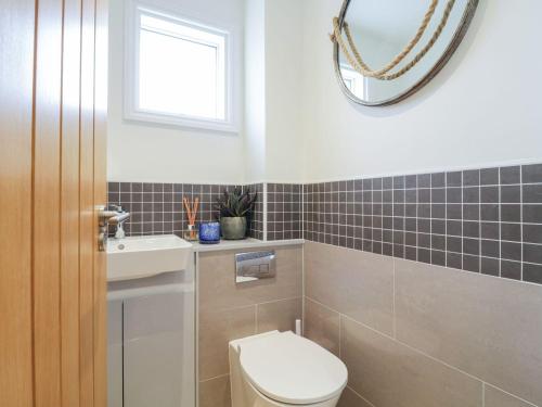 a bathroom with a toilet and a sink and a mirror at Sundowners in Southwold