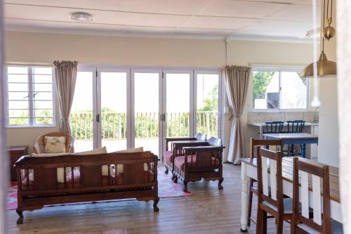 a living room with tables and chairs and windows at A Stone's Throw from the Ocean in Seafield