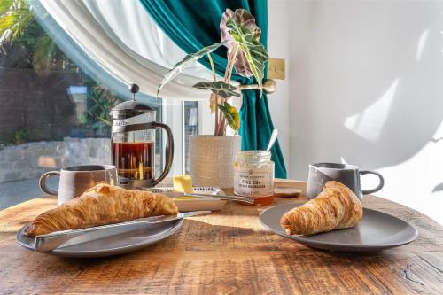 a table with two plates of croissants and coffee cups at 5 min walk to beach with parking and private sauna in Falmouth