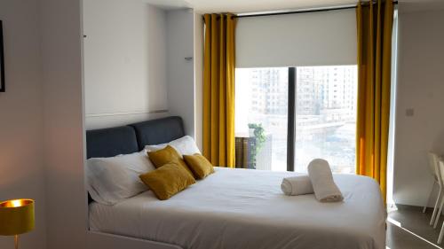 a bedroom with a bed with yellow curtains and a window at E1 Suites & Spa aparthotel style - Gym & Spa in Gibraltar