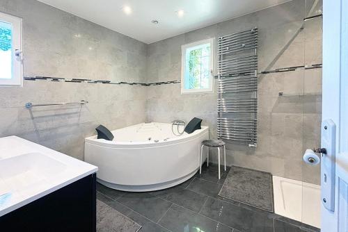 La salle de bains est pourvue d'une baignoire blanche et d'une douche. dans l'établissement VILLA CHEZ-NOUS C'est chez vous, piscine, plages et golfs, à Saint-Raphaël