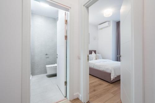 a white bedroom with a bed and a bathroom at UpHome Suites in Bucharest