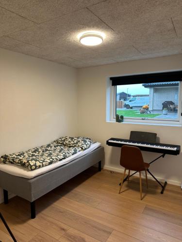 a bedroom with a bed and a desk and a keyboard at Moderne nybygget in Holstebro