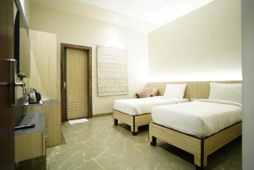 a hotel room with two beds and a television at Hotel City Grand Varanasi in Varanasi