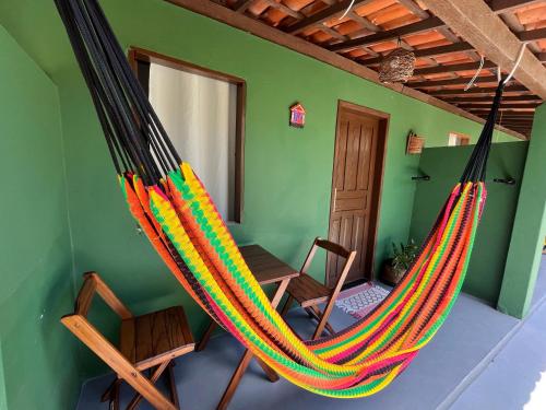 a hammock in a room with a table at Caju com Mel Hospedagem in Moreré