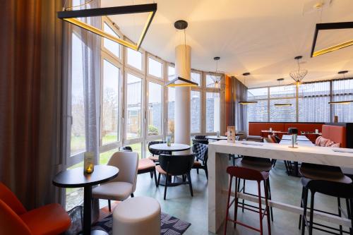 a restaurant with tables and chairs and large windows at Holiday Inn - the niu, Blade Solingen by IHG in Solingen