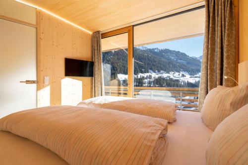 a bedroom with two beds and a large window at Walserkreuz Suiten in Hirschegg