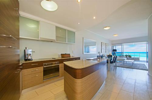 a kitchen with a counter and a table with chairs at Waves Maroochy River in Maroochydore