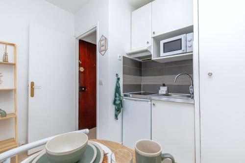 Una pequeña cocina con una mesa y un microondas. en Studio cosy 2P - Proche Versailles/Paris, en Le Chesnay