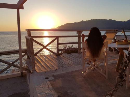 a woman sitting in a chair watching the sunset at Mochlos Beach Villa Seafront house in Mochlos