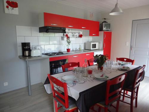 a kitchen with a table with chairs and red cabinets at Chalet Fuchsia à Argentat in Argentat