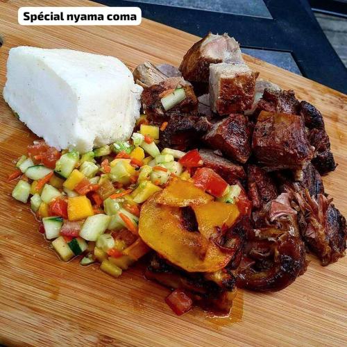 a plate of food with meat and vegetables on a cutting board at REBERO RESORT Ltd in Kigali