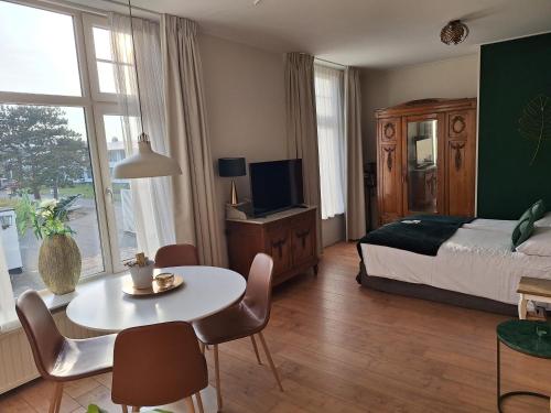 a bedroom with a bed and a table and a tv at Prins Appartementen in Egmond aan Zee