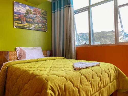 a bedroom with a bed with a yellow comforter and windows at Hotel Jazen in Huaraz
