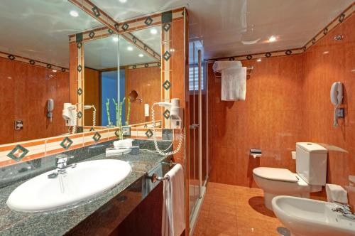 a bathroom with a sink and a toilet and a mirror at Hotel Palma Bellver , Affiliated by Meliá in Palma de Mallorca