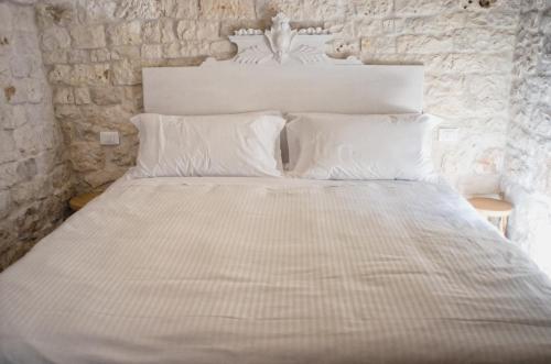 a bed with white sheets and pillows in a room at Borgo Santa Clara in Cisternino