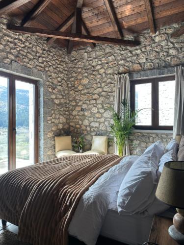 a bedroom with a large bed in a stone wall at Wood & Stone Guesthouse in Khrisovítsion