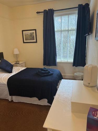 a bedroom with a bed and a window with blue curtains at The Woodland's Hotel in Bradford