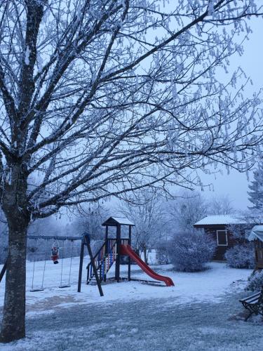 - une aire de jeux dans une cour recouverte de neige dans l'établissement Chalet Edelweis, à Plombières-les-Bains