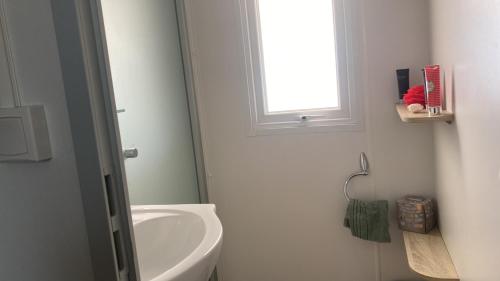 une salle de bain avec un lavabo et des toilettes et une fenêtre dans l'établissement Mobile Home de Valérie 