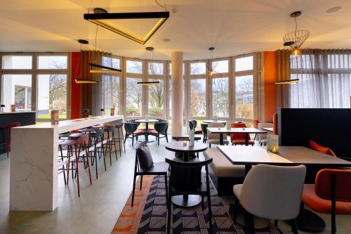 a restaurant with tables and chairs and windows at Holiday Inn - the niu, Blade Solingen by IHG in Solingen