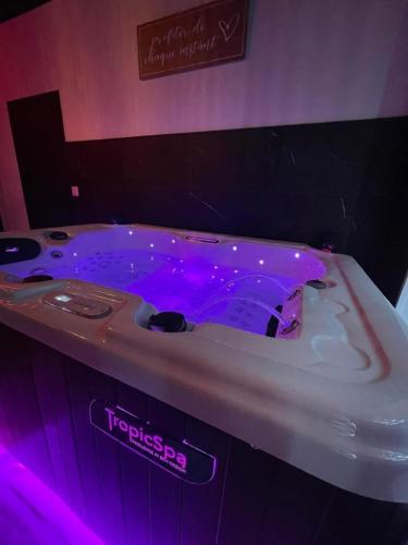 une baignoire avec des lumières violettes dans une salle de bain dans l'établissement Au spa de clem, à Guemps