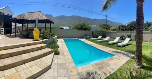 a swimming pool with chairs and a gazebo at Bird's View Guest Accommodation in Hermanus