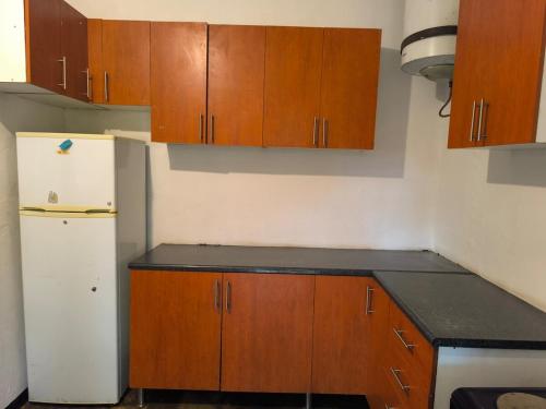 a kitchen with wooden cabinets and a white refrigerator at Serene Home in Lilongwe