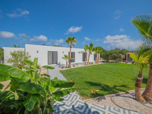 a white house with palm trees and a yard at CasaNoa Luxury Villa Bed and Breakfast in Jávea