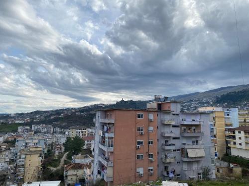 a building in a city under a cloudy sky at Mateo Apartment in Gjirokastër