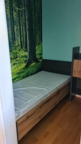 a bed in a room with a painting of a forest at Appartement 7 101 in Goslar