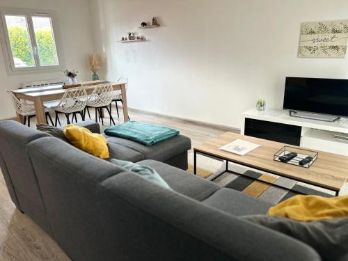 salon z kanapą i stołem w obiekcie Maison Mitoyenne avec cour + parking w mieście Sainte-Savine