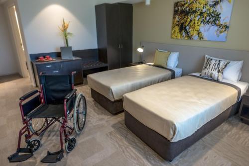 a bedroom with two beds and a wheelchair in a room at Lithgow Workies Club Motel in Lithgow