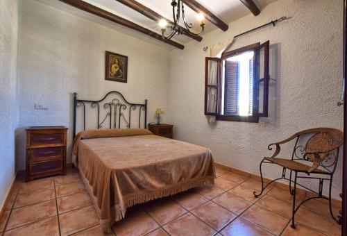 una camera da letto con un letto, una sedia e una finestra di Cortijo Los Alazores, authentic cortijo with private pool a Loja