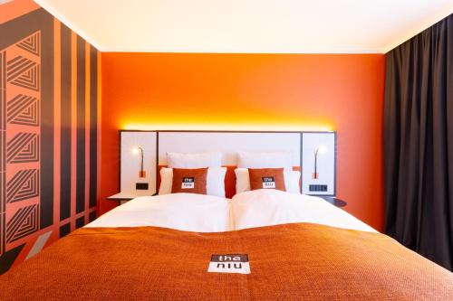 a hotel room with a bed with an orange wall at Holiday Inn - the niu, Blade Solingen by IHG in Solingen