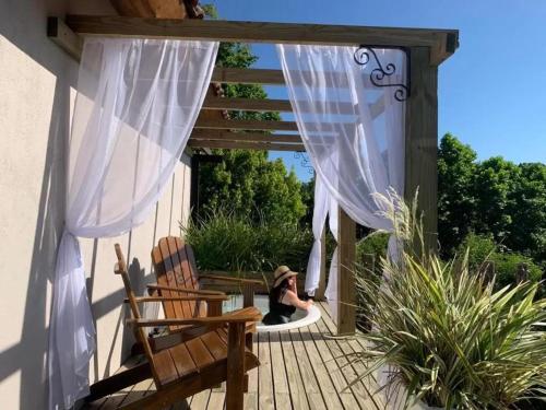 a woman sitting on a wooden deck with a pergola at Chalé Sunset com Hidro, lareira, piscina, cavalo, trilha, tiro ao alvo in Bento Gonçalves