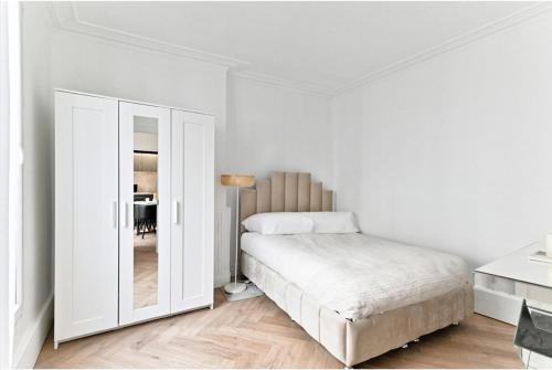 une chambre blanche avec un lit et un miroir dans l'établissement Modern apartment Paris Moulin Rouge, à Paris