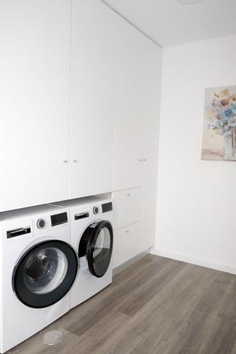 a washing machine in a white laundry room with a painting at Ruhiges Modernes Haus Parkplatz WLAN Whirlpool in Aveiro