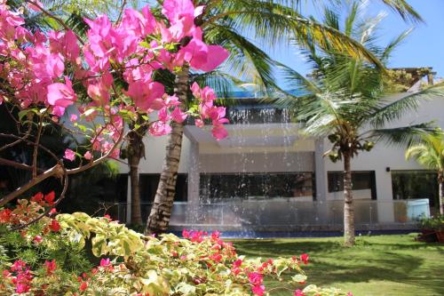 a building with pink flowers in front of a fountain at SUNSOL UNIK Luxury Hotel in Porlamar